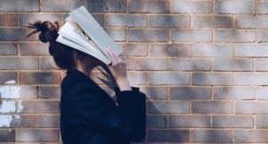 woman covering face with book
