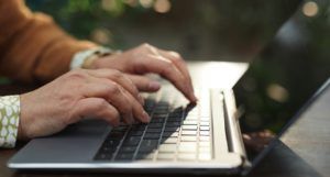 image of hands typing on a black and silver laptop computer