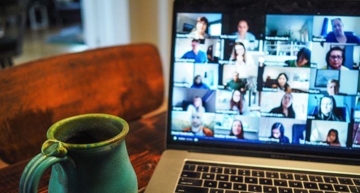 coffee and laptop on table with zoom call of panelists or people