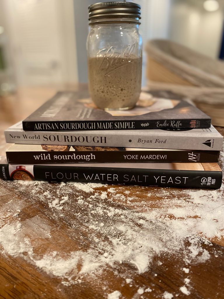 Sourdough starter in jar on top of four cookbooks