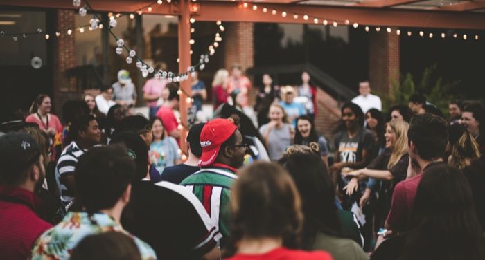 view of a crowded outdoor social gathering or party with a string of lights overhead