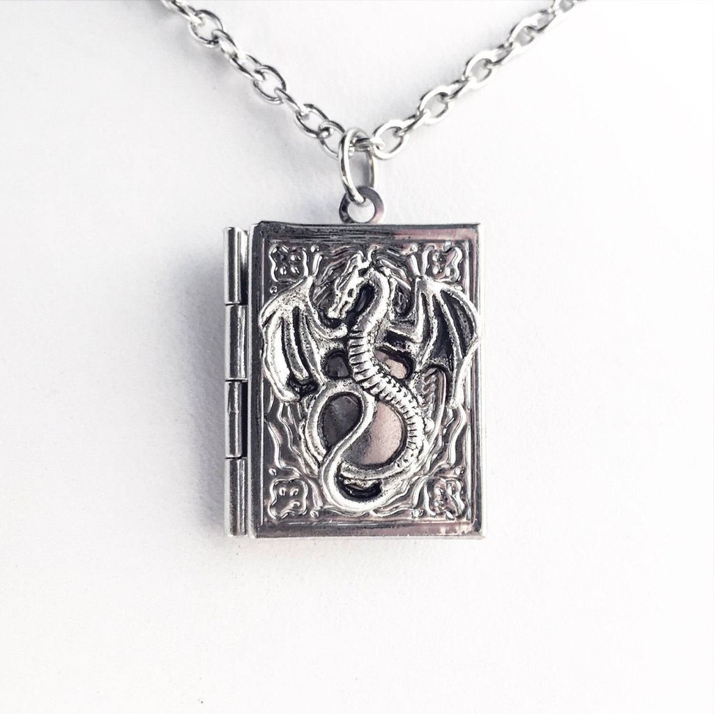 A book medallion necklace with a dragon on the front