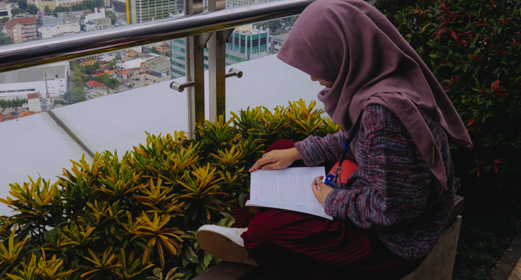 indonesan woman in hijab reading a book