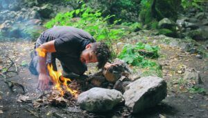 A person making a camp fire in the woods