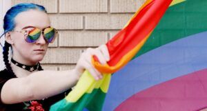 image of a woman in sunglasses holding a rainbow flag