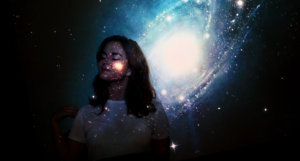 a woman standing in front of a projection of a galaxy