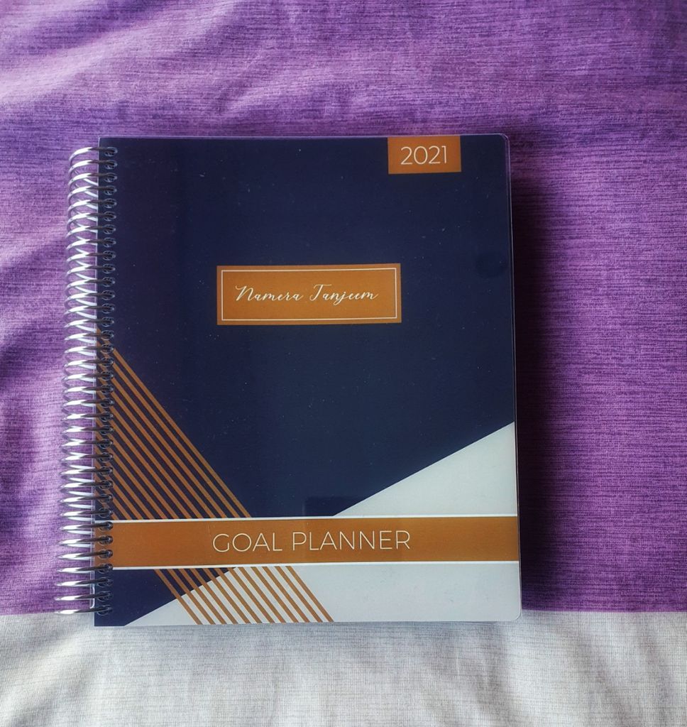 Photo of Plum Paper Planner against a purple and white fabric background