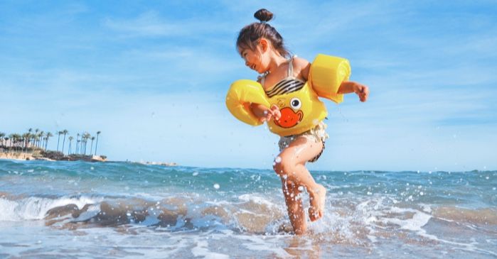 little girl child splashing in the ocean at the beach