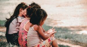 image of three young children sitting together in the grass