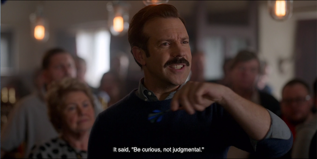 Ted Lasso at darts with the caption, "It said, 'Be curious, not judgmental.'"