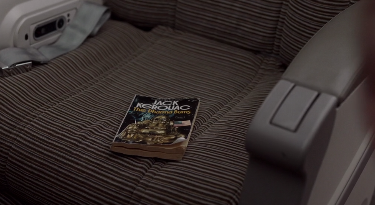 A still of Ted Lasso episode 1 showing a worn copy of The Dharma Bums on Ted's plane seat