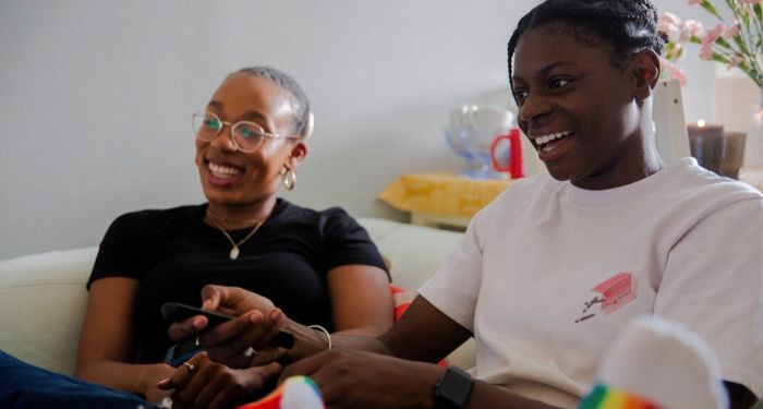 black queer lesbian couple smiling and watching television at home