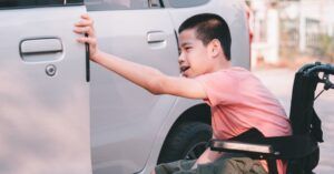 disabled child using a wheelchair opening a car door