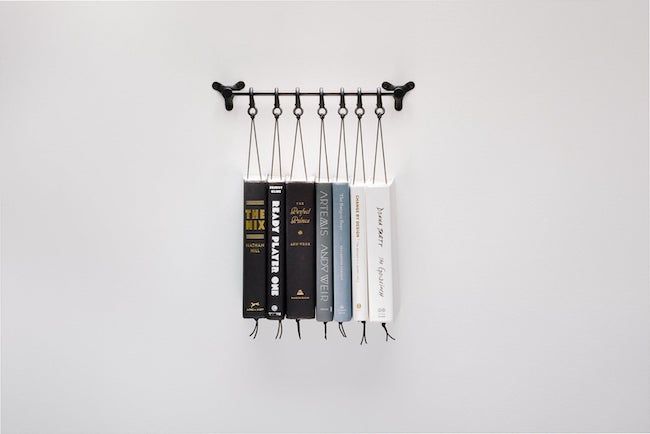 Industrial book rack, with books suspended off a metal bar