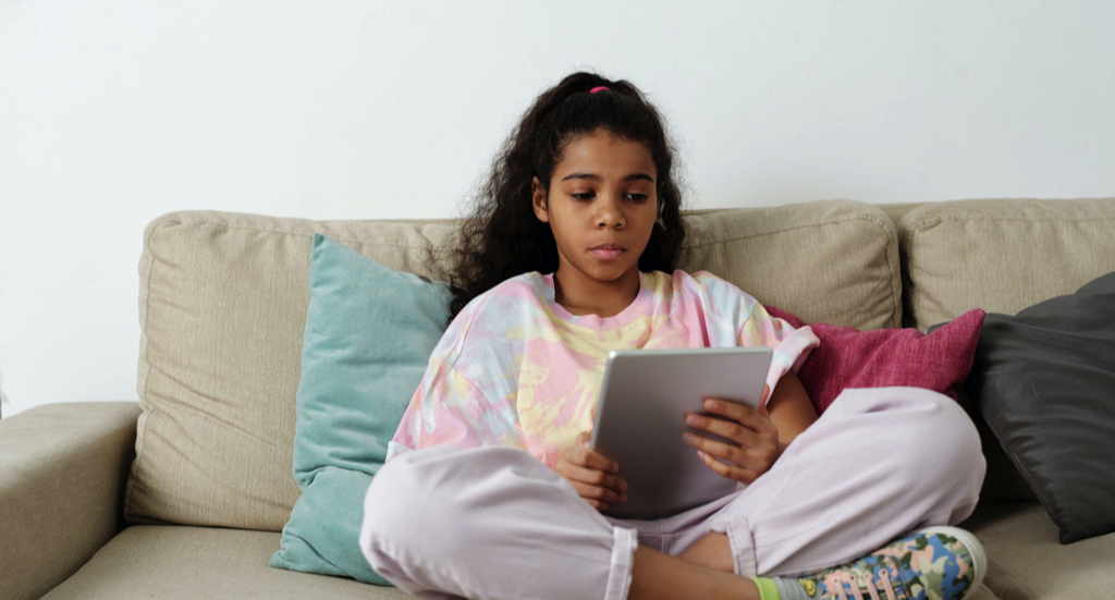 image of a young girl in a tie-dye shirt reading a tablet on a couch https://www.pexels.com/photo/girl-in-pink-shirt-sitting-on-couch-4144042/