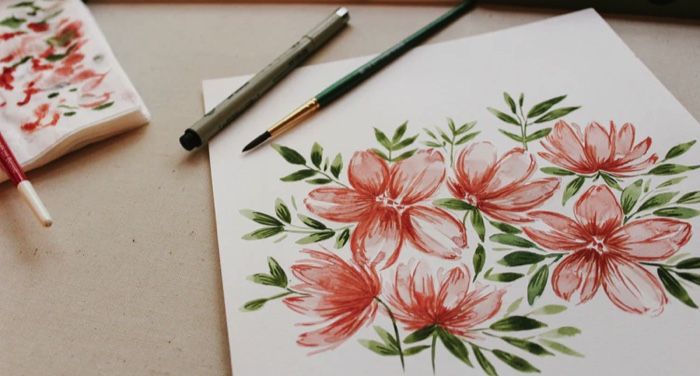 a painting of red and pink flowers on white paper next to various art supplies