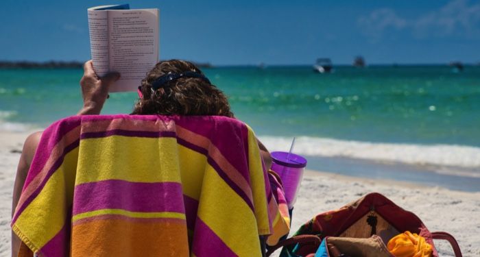 a person reading in a chair in the sand a. the beach https://unsplash.com/photos/MABt_EhXT6E