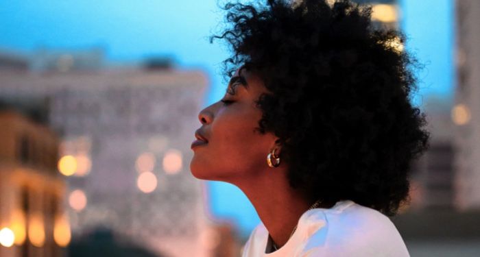 black woman lifting her head against city backdrop