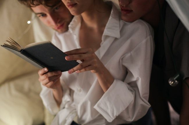 three people reading one book