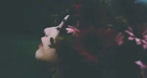 a woman wearing a crown of dark red and pink flowers