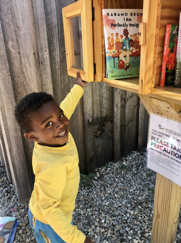 Image of a young Black boy opening a little free library. Image used with permission from Sarah Kamya, founder of Little Free Diverse Libraries