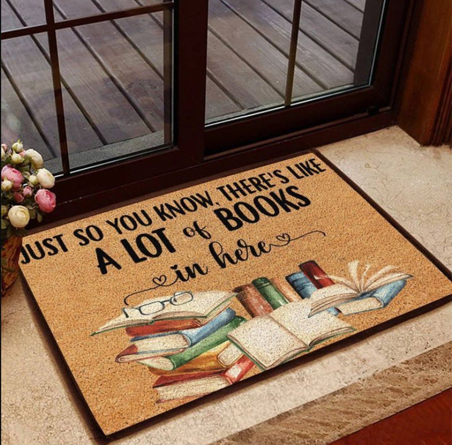 Brown doormat with black text reading "Just so you know, there's like a lot of books in here," with a stack of books below. 