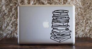 a silver laptop computer with a vinyl book stack decal