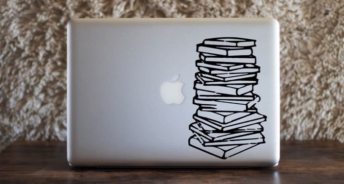 a silver laptop computer with a vinyl book stack decal