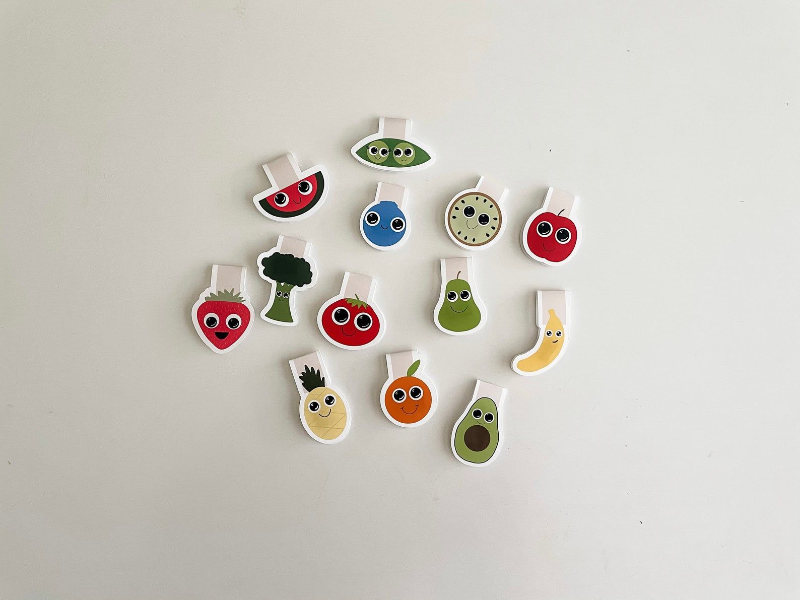 A collection of magnetic bookmarks in the shape of fruit and vegetables. Each has big, oversized eyes. 