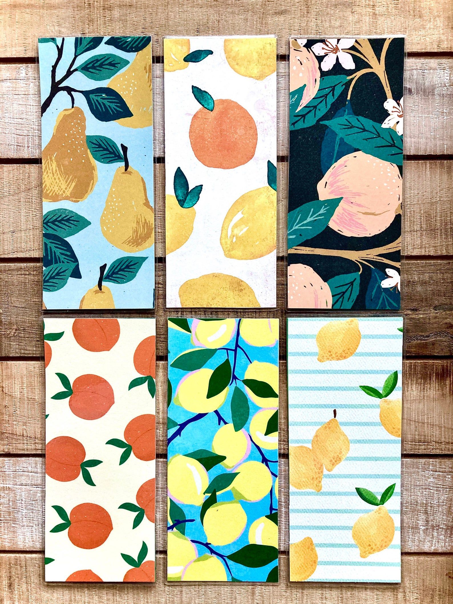Image of six different handmade fruit bookmarks, featuring pears, peaches, and lemons. 