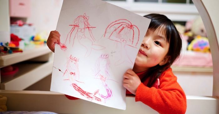 little girl child showing a drawing to the camera