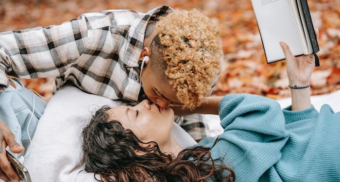 a photo of a queer couple kissing with book