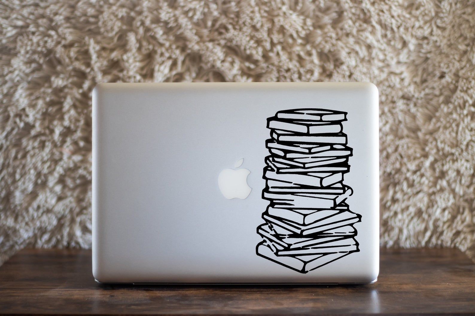 a silver laptop computer with a vinyl book stack decal
