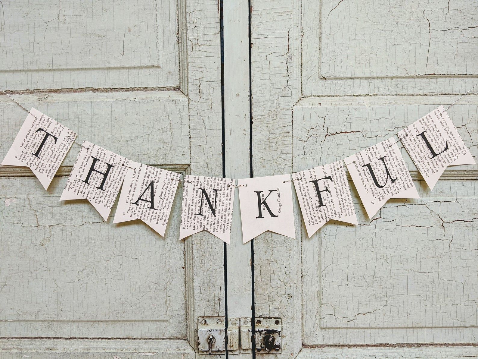 Banner made out of old book pages. Each page has a letter, spelling out "thankful."