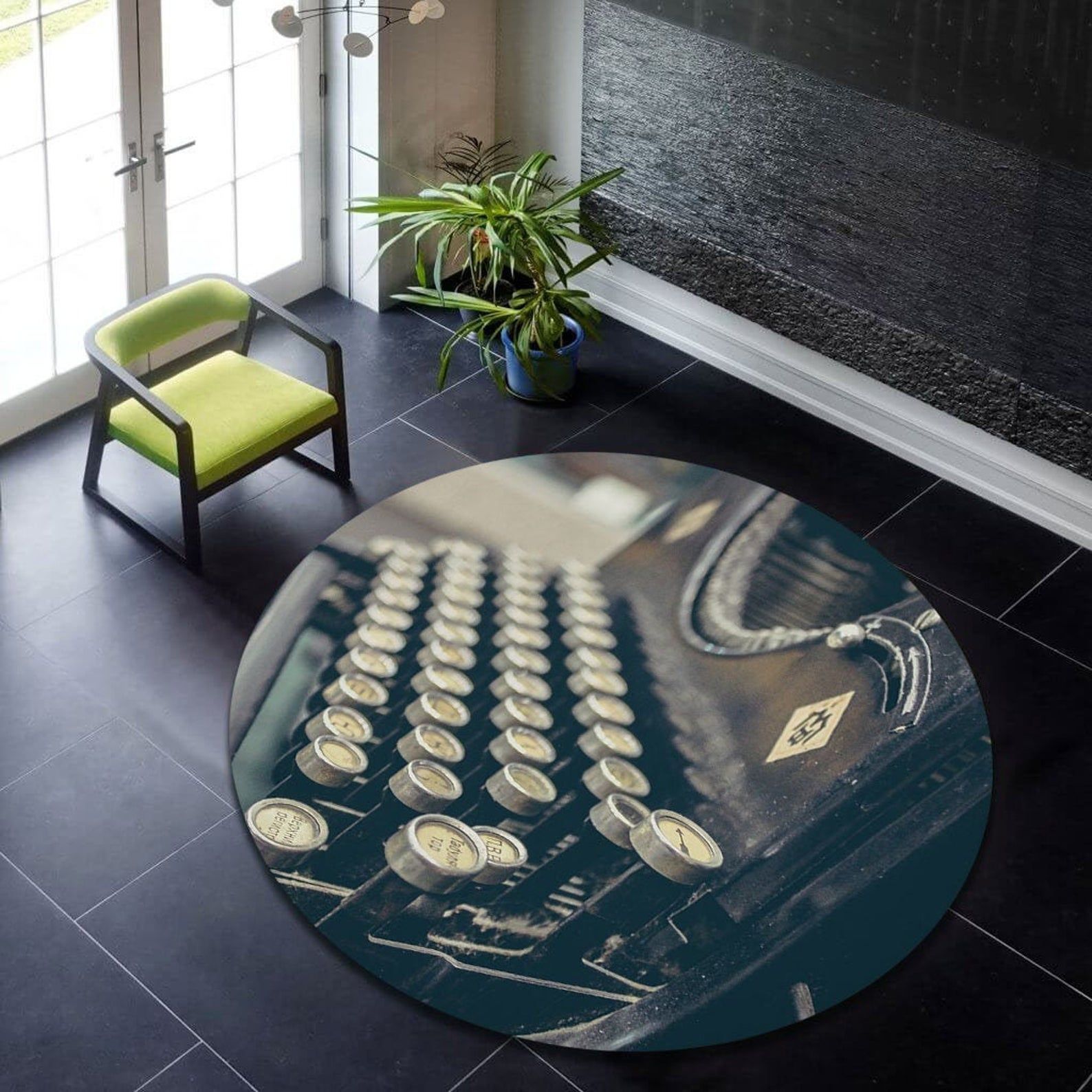 An image of a modern space with dark tile floors, a green rug, and a plant. At the center of the room is a large round rug featuring a close up of typewriter keys.