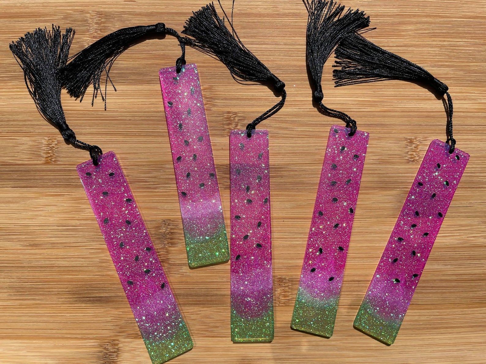 Image of five resin bookmarks, all painted like a slice of watermelon. 