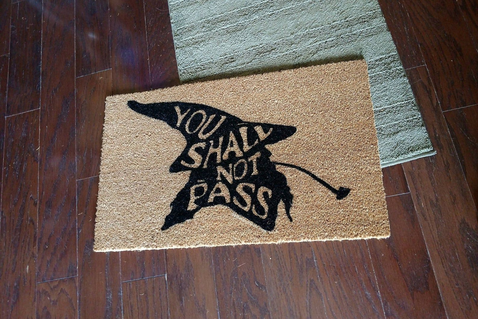 Image of doormat with a wizard-like silhouette and inside of it, the words "you shall not pass." 