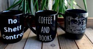 Image of three black coffee mugs with book themes