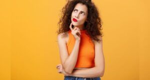 Golden yellow background with a curly-haired woman making a thinking face