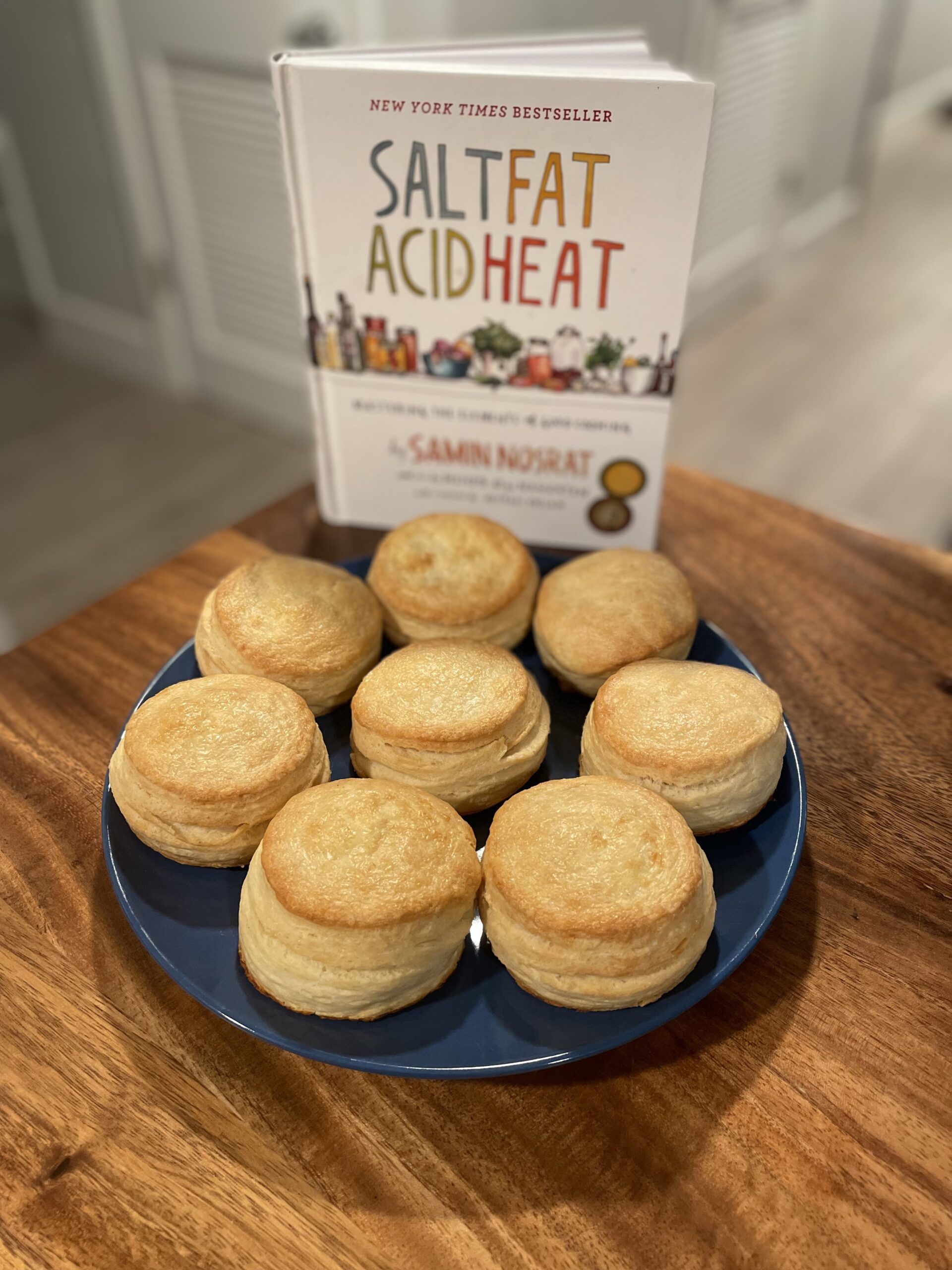 Salt, Fat, Acid, Heat cookbook with a plate of buttermilk biscuits