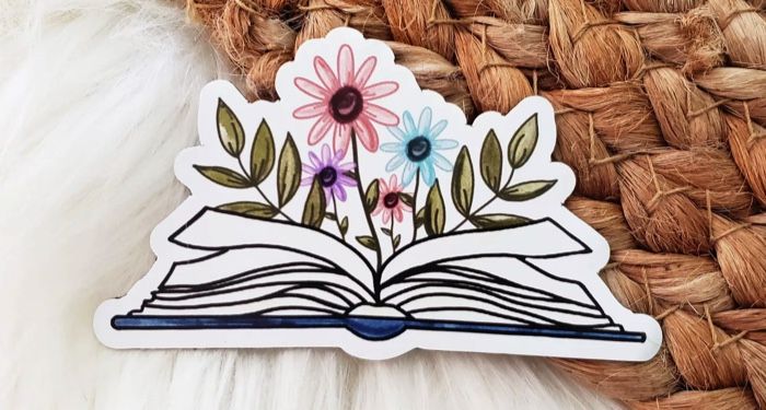 a magnet featuring an open book with pink, blue, and purple flowers growing from the center