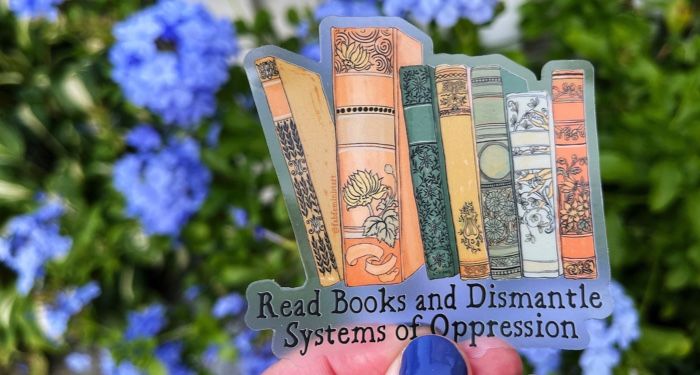 A clear sticker that depicts beautiful antique book spines and reads "Read Books and Dismantle Systems of Oppression"