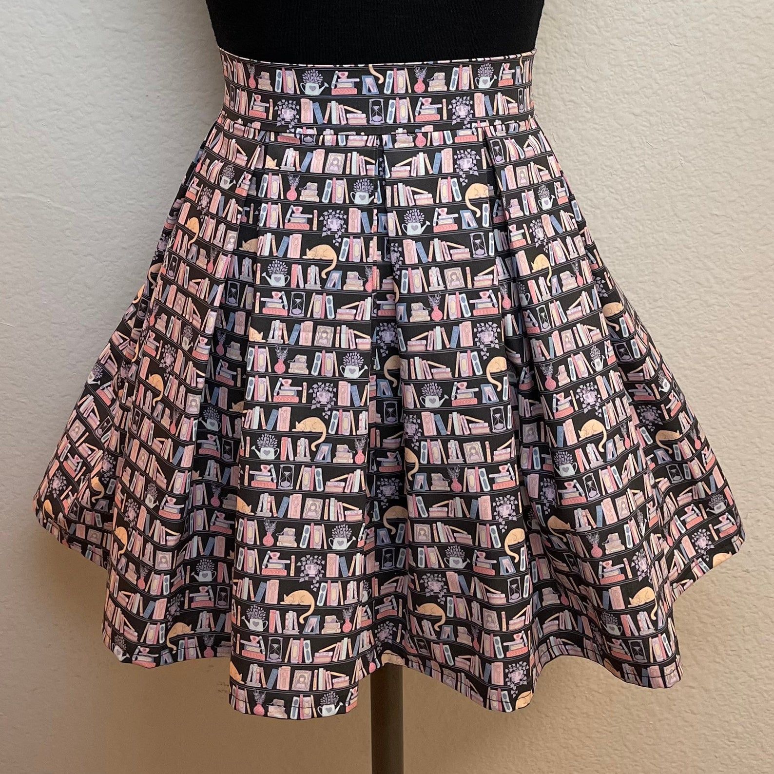 Black skirt decorated with a motif of pink books, plants, and cats.