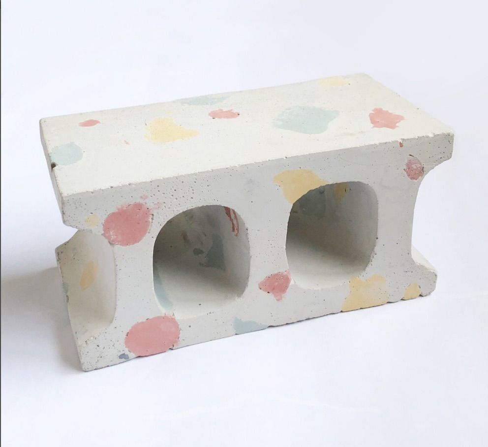 Cinder block painted white with terrazzo-like flecks in pink, blue, and yellow. 