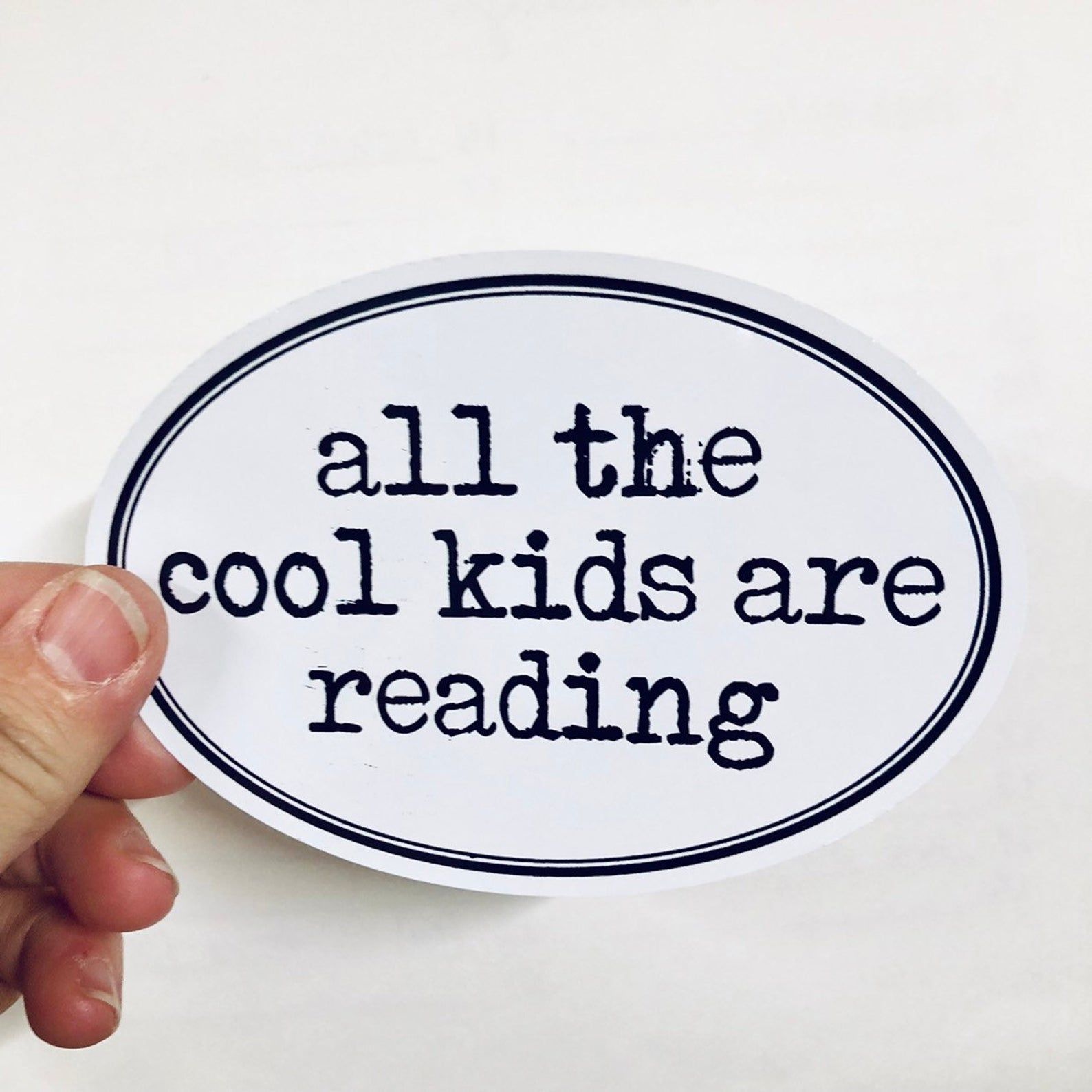 Black and white oval sticker that reads "all the cool kids are reading"