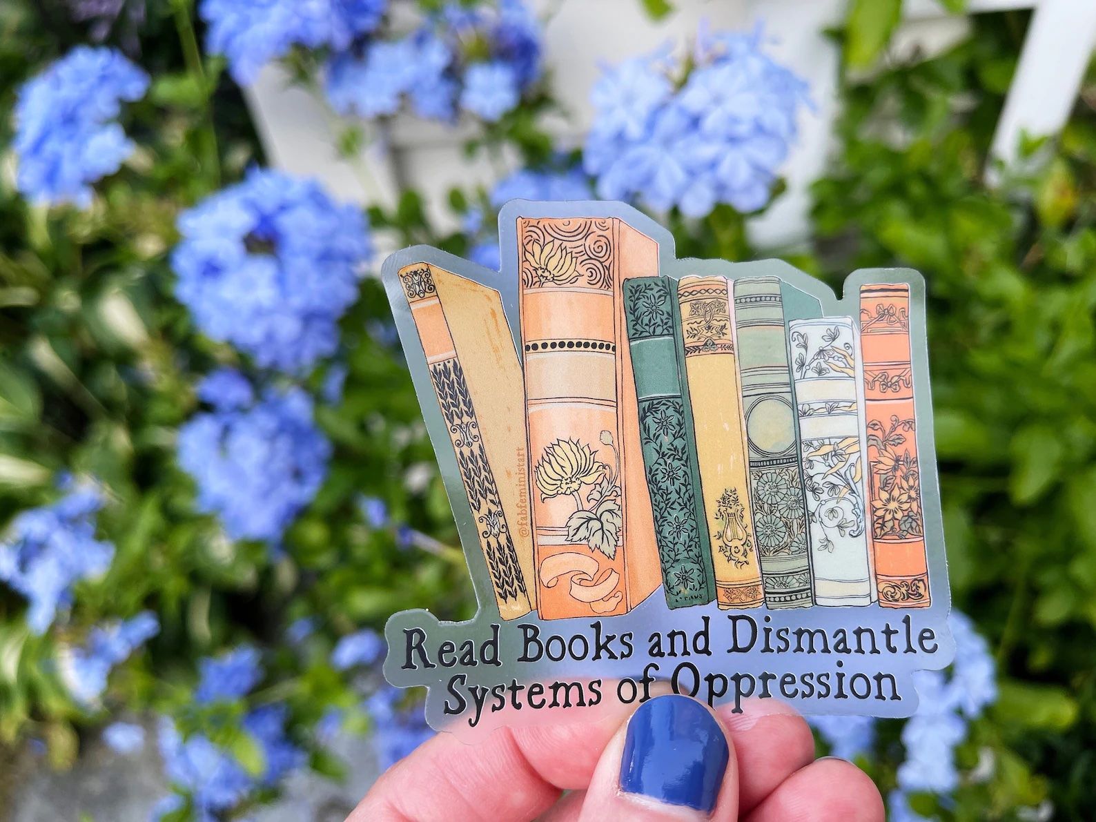 A clear sticker that depicts beautiful antique book spines and reads "Read Books and Dismantle Systems of Oppression"
