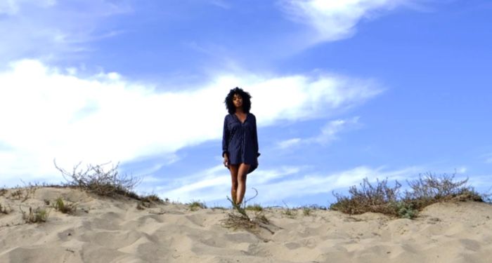 a woman in a dark blue dress short standing in the desert