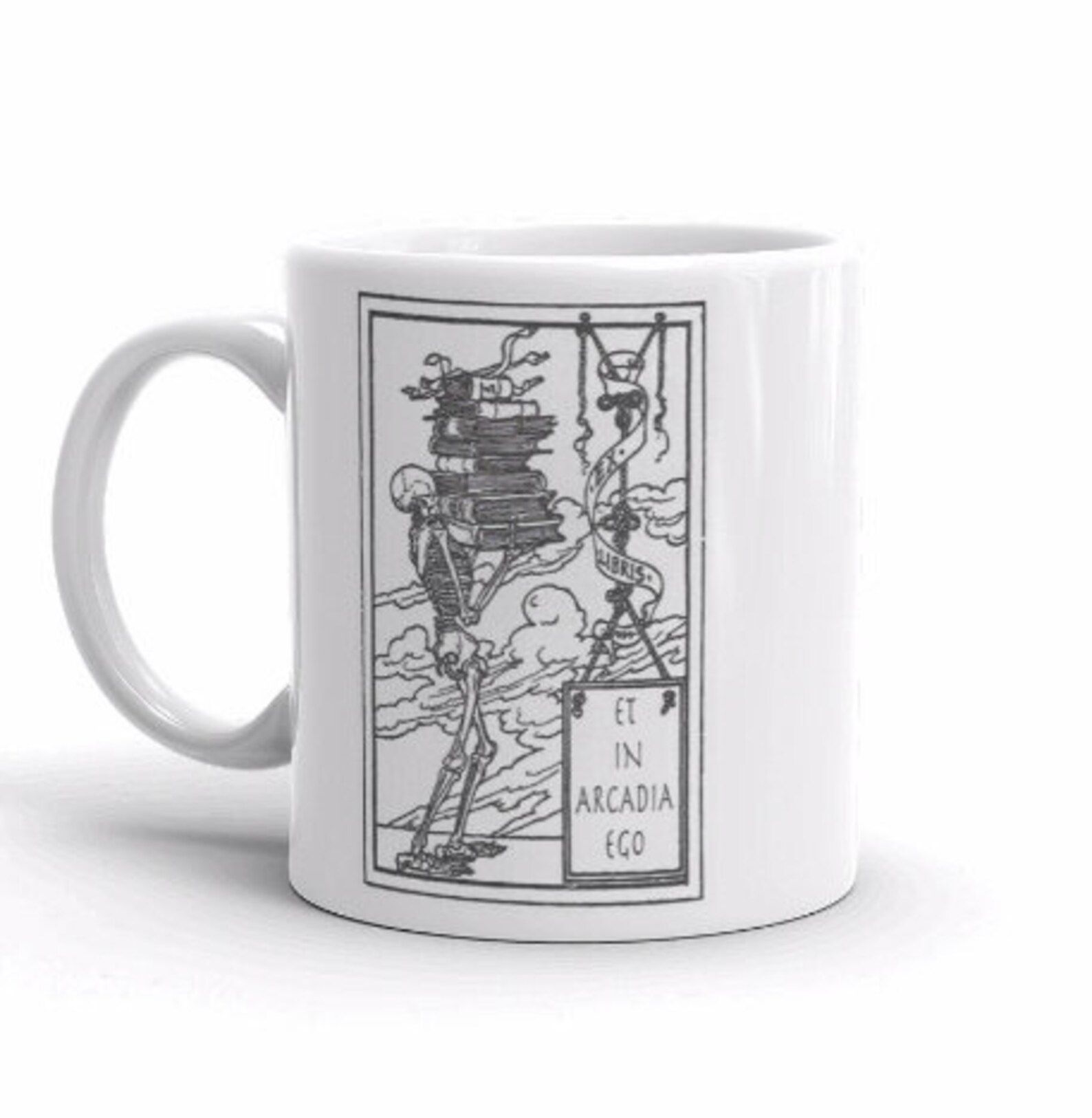 Image of a white mug. The design on the mug features a skeleton holding books, with a sign reading "et in arcadia ego." 