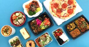 assortment of foods in takeout containers against a blue backdrop