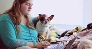 image of girl in blue jacket holding white and brown short coated puppy